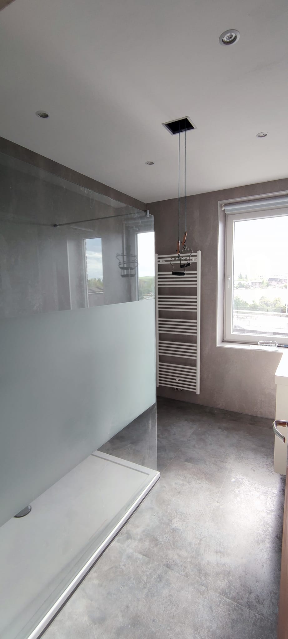 Salle de bain design douche à l'italienne murs et sol béton ciré radiateur sèche-serviettes moderne