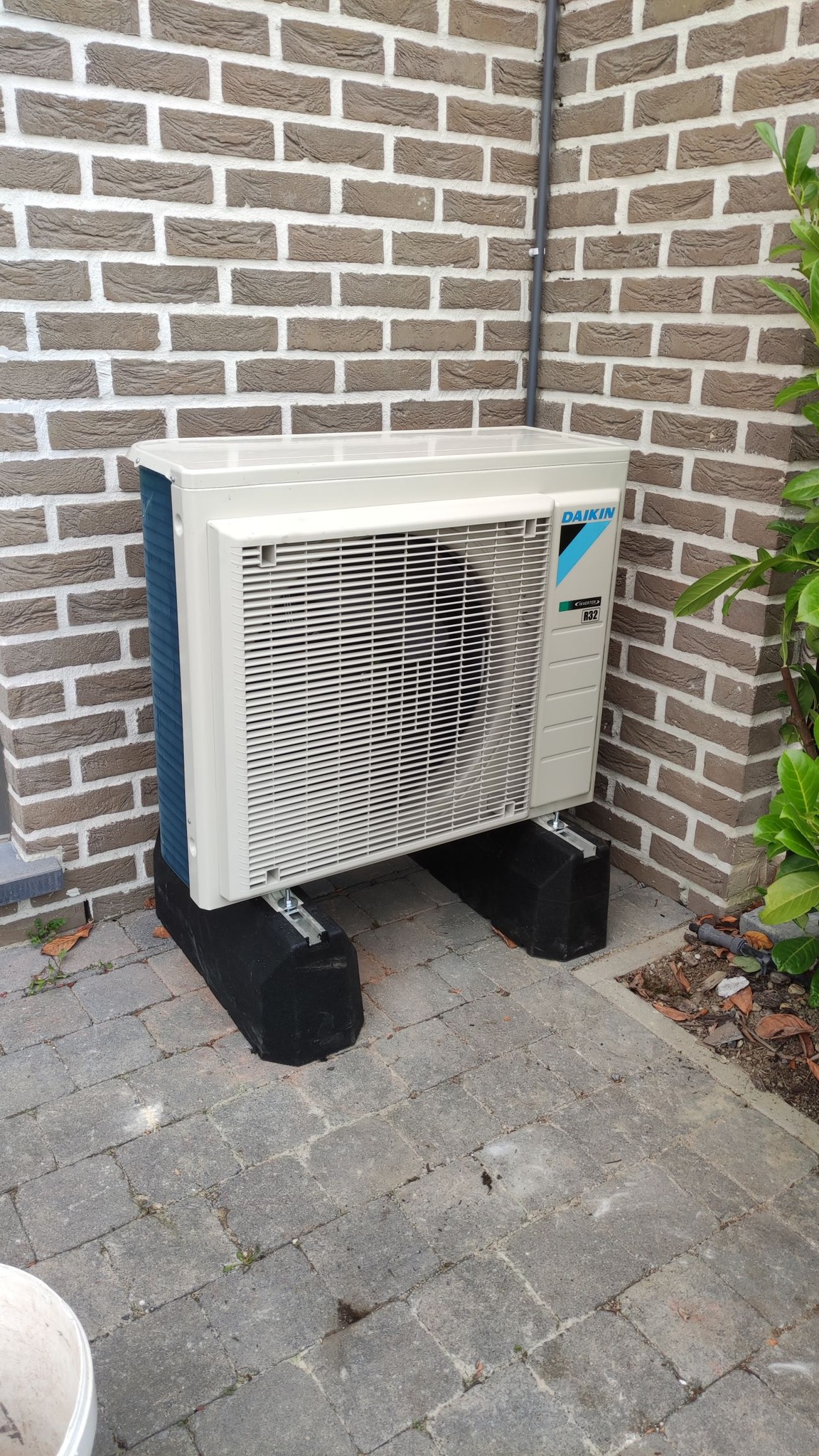 Unité extérieure Daikin pompe à chaleur air-eau ou climatisation installation au sol sur plots mur briques